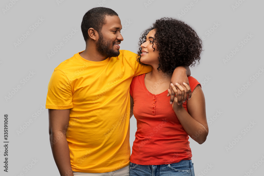 relationships and people concept - happy african american couple hugging over grey background relationships and people concept - happy african american couple hugging over grey background