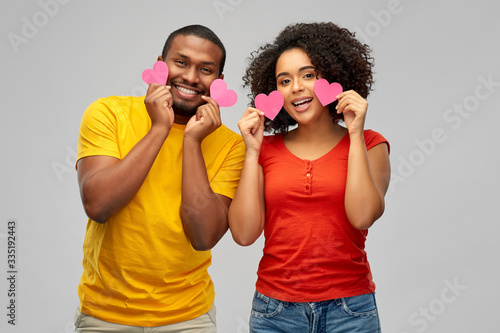 love, relationships and valentines day concept - happy african american couple with hearts having fun over grey background
