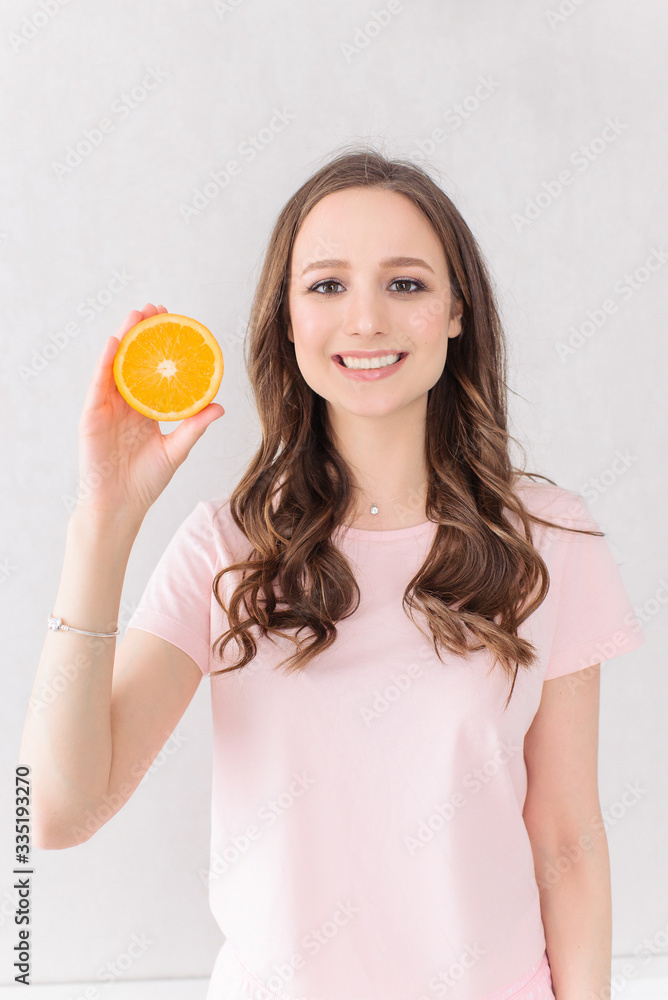 Attractive female in rose t-shirt holding orange fruit over white background Attractive female in rose t-shirt holding orange fruit over white background