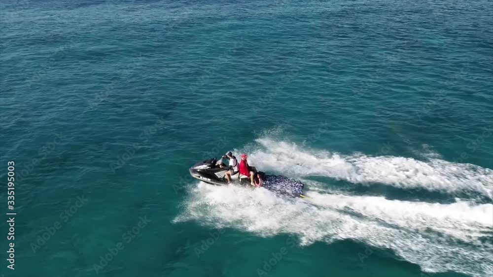 Aerial view, life guard on jet ski performing rescue operation off the coast of Bali, Indonesia, in blue water, slow motion Aerial view, life guard on jet ski performing rescue operation off the coast of Bali, Indonesia, in blue water, slow motion