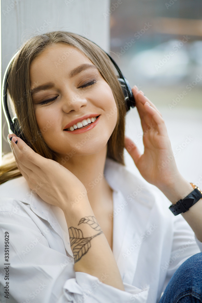 Smiling young woman at the cafe with headphones listening to music