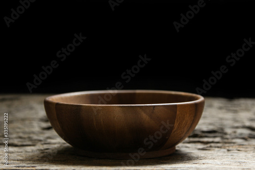 Wooden bowl on wooden black background.