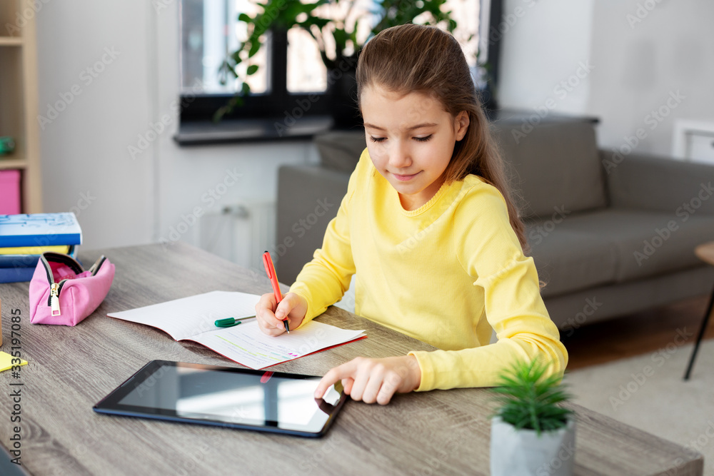 children, education and distant learning concept - happy student girl with tablet pc computer writing to notebook at home