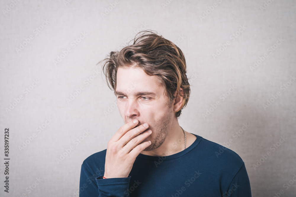 A man yawns. Gray background A man yawns. Gray background