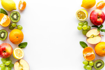 Fresh fruits background with citruses, apple, kiwi and grape on white table top-down frame copy space