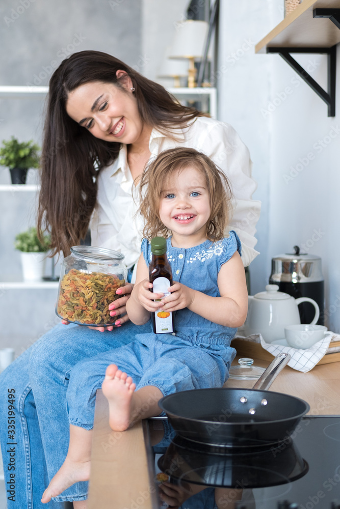 happy mom and daughter are cooking in the kitchen. mom brunette in ...