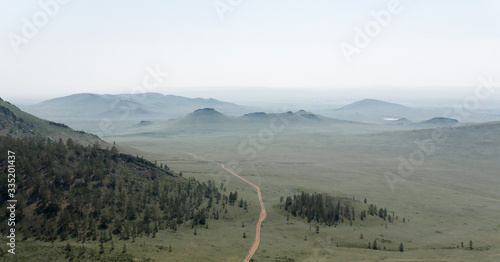 Mountains and hills in the early, cool morning against a gray sky. Russia, Buryatia