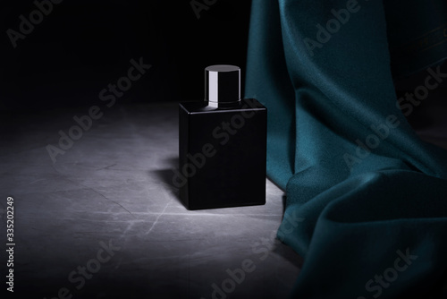 Packaging profumo su uno sfondo di nero, un piano di marmo e un tessuto verde, foto pubblicità moda