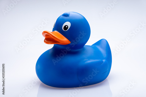 Blue rubber toy duck with orange beak isolated in front of a white background.