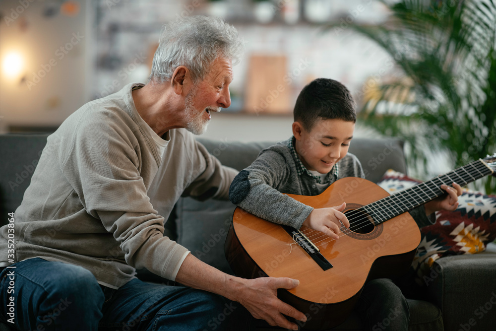 Fototapeta premium Grandpa and grandson playing guitar. Grandfather and grandson enjoying at home. 