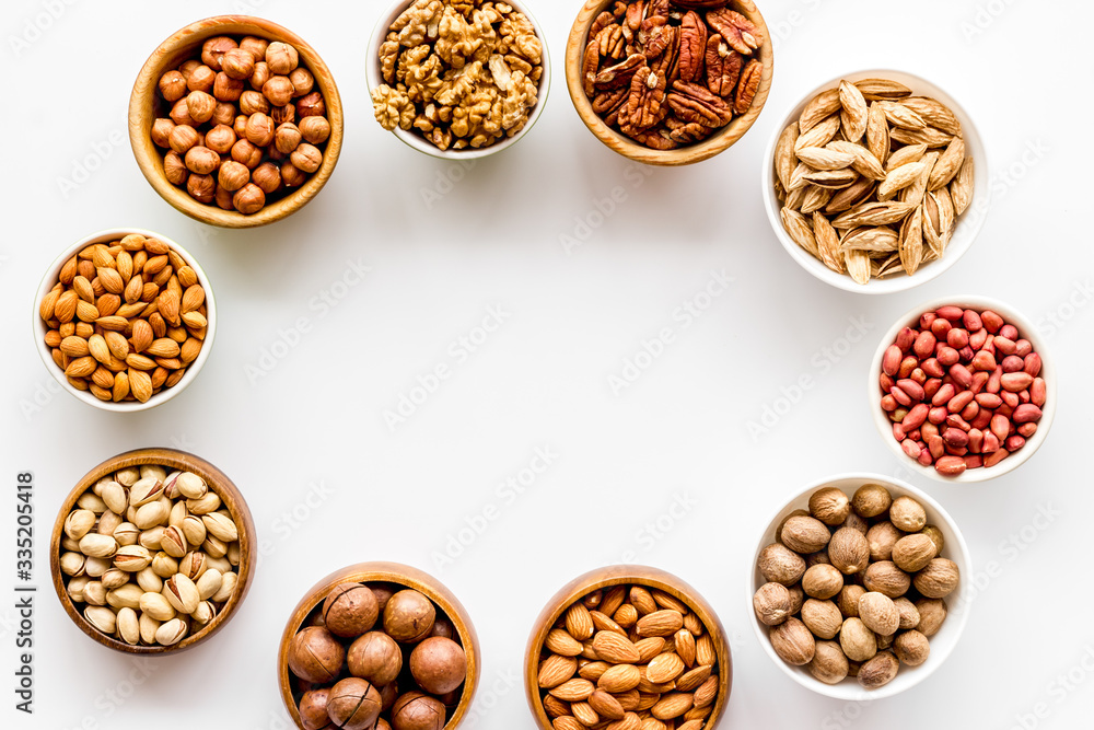 Fototapeta premium Nuts set in bowls on white background top-down frame copy space