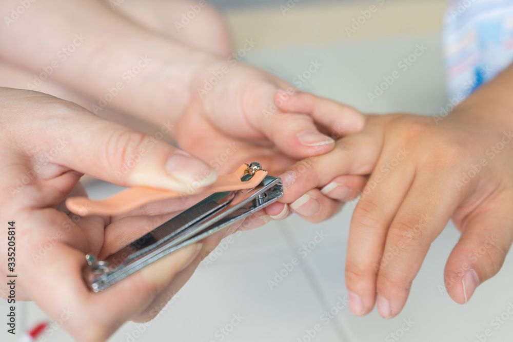 Mother cutting son nails using the clippers.