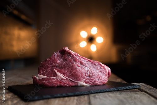 Taglio di carne di manzo su piatto di ardesia, tavolo in legno e background con luce calda photo