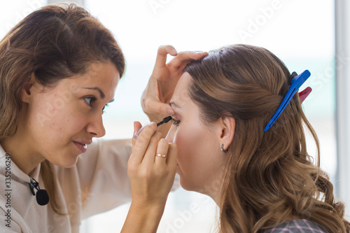 Beauty and cosmetics concept - Makeup artist doing professional make up of young woman