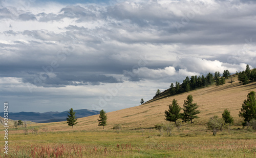 Picturesque mountains and hills on a cloudy day against the background of dark clouds. Mongolia