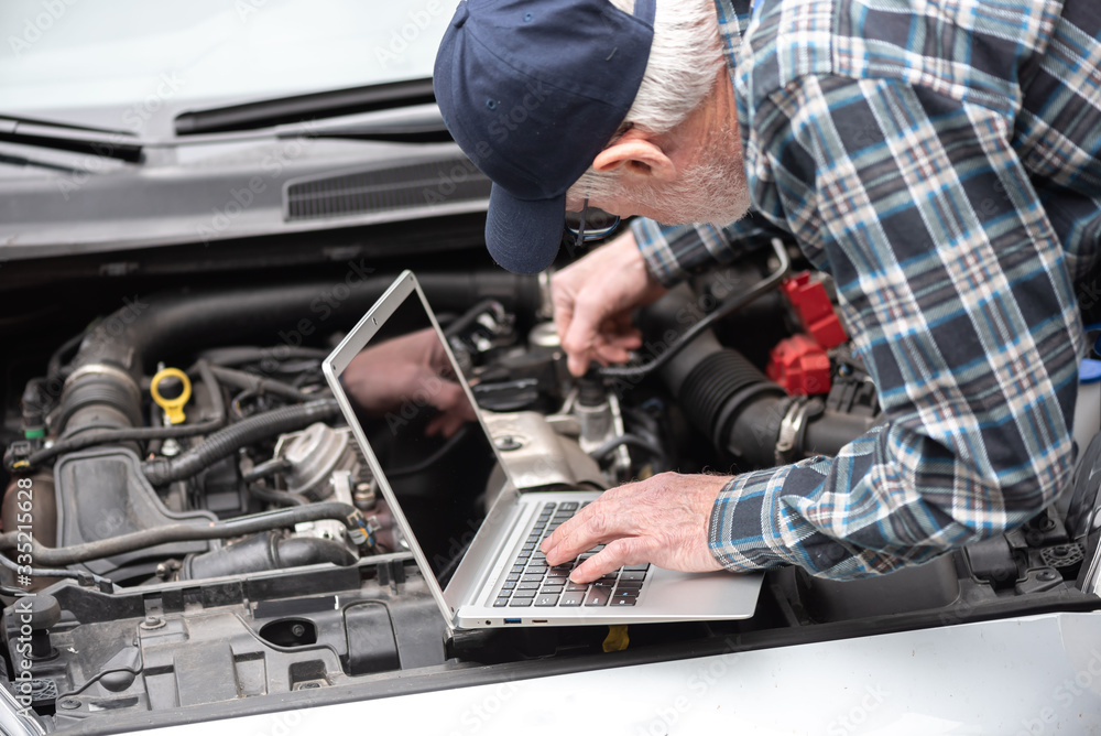 Mechanic using laptop for checking car engine Mechanic using laptop for checking car engine