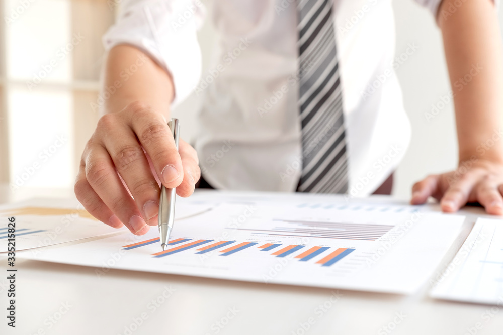 A business man is sitting at a desk and calculating financial graphs about real estate investment expenditures A business man is sitting at a desk and calculating financial graphs about real estate investment expenditures