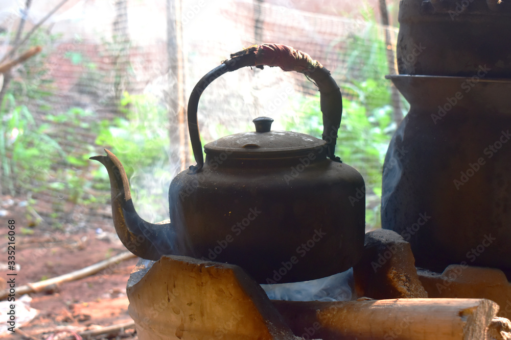 The old aluminum kettle on the stove with smoke in countryside kitchen. The old aluminum kettle on the stove with smoke in countryside kitchen.