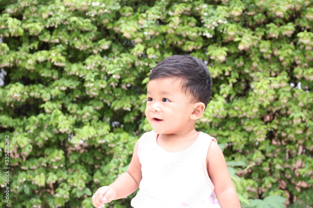 ASEAN children sitting smiling background with green leaves. 8 months old. ASEAN children sitting smiling background with green leaves. 8 months old.