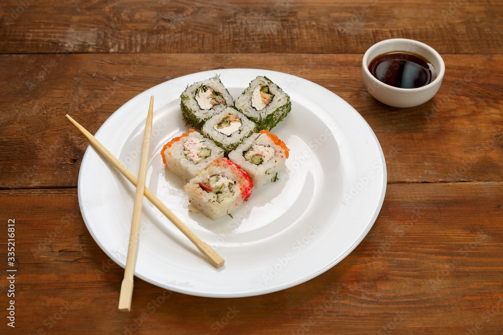 Assorted different fish rolls on a white plate soy sauce. Assorted different fish rolls on a white plate soy sauce.