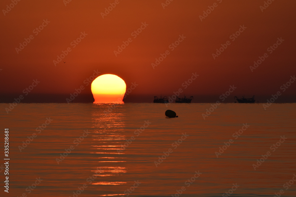 Il sorgere del sole con barche che pescano a Riccione 