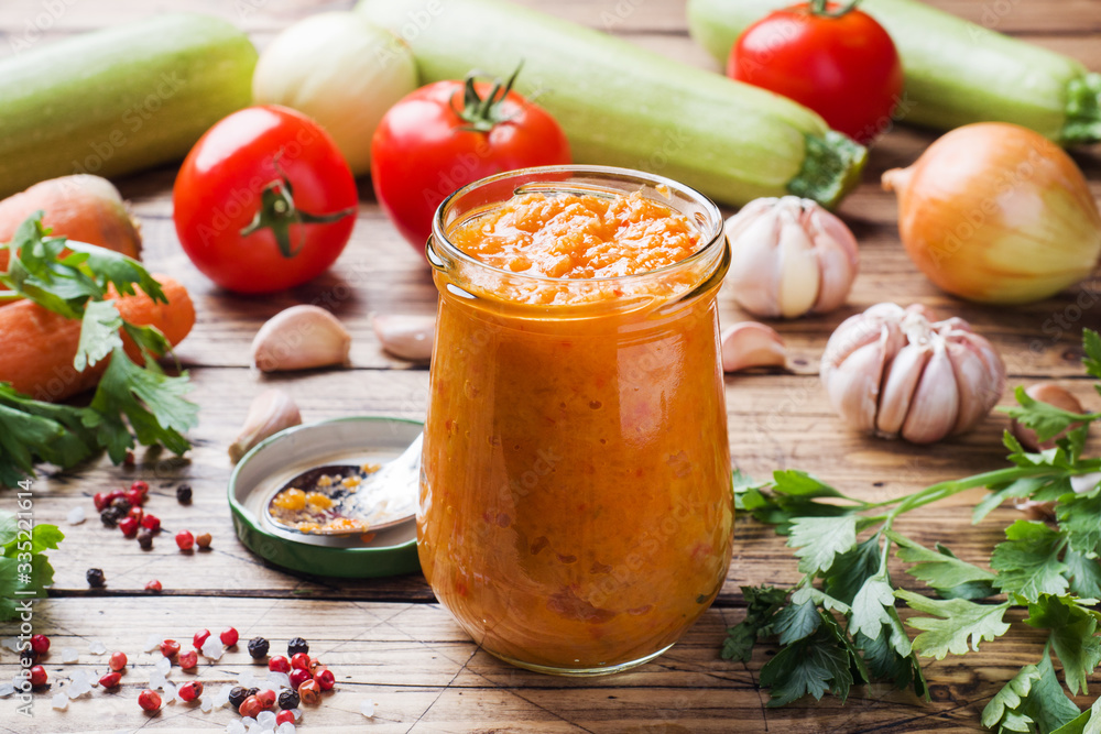 Homemade caviar from zucchini tomatoes and onions in a glass jar on a wooden background. Homemade production canning, canned stewed vegetable. Homemade caviar from zucchini tomatoes and onions in a glass jar on a wooden background. Homemade production canning, canned stewed vegetable.