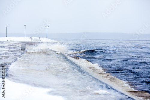 Embankment. Winter storm on the coast. Cold water and a pedestrian area near the water. Landscape with a promenade line near the lake.