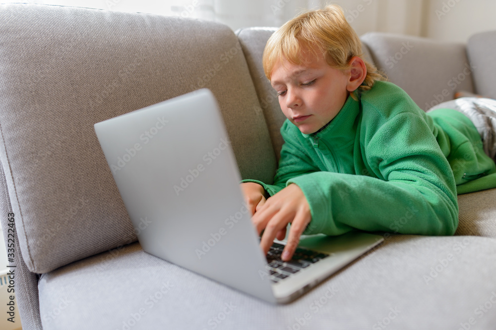 Young handsome boy lying down while using laptop on the couch at home Young handsome boy lying down while using laptop on the couch at home