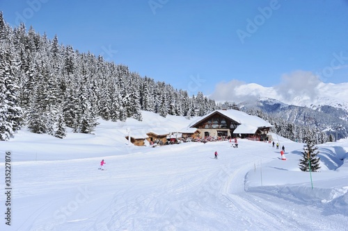 Beautiful ski resort with wooden chalet next to ski slope © raeva