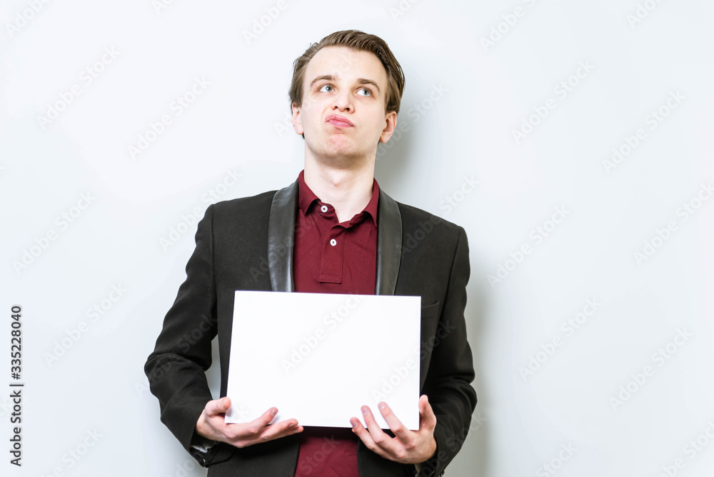 Disgusted, not happy young business man in red polo shirt and blazer holding blank A4 sheet of paper for slogan. Lose a job concept background Disgusted, not happy young business man in red polo shirt and blazer holding blank A4 sheet of paper for slogan. Lose a job concept background