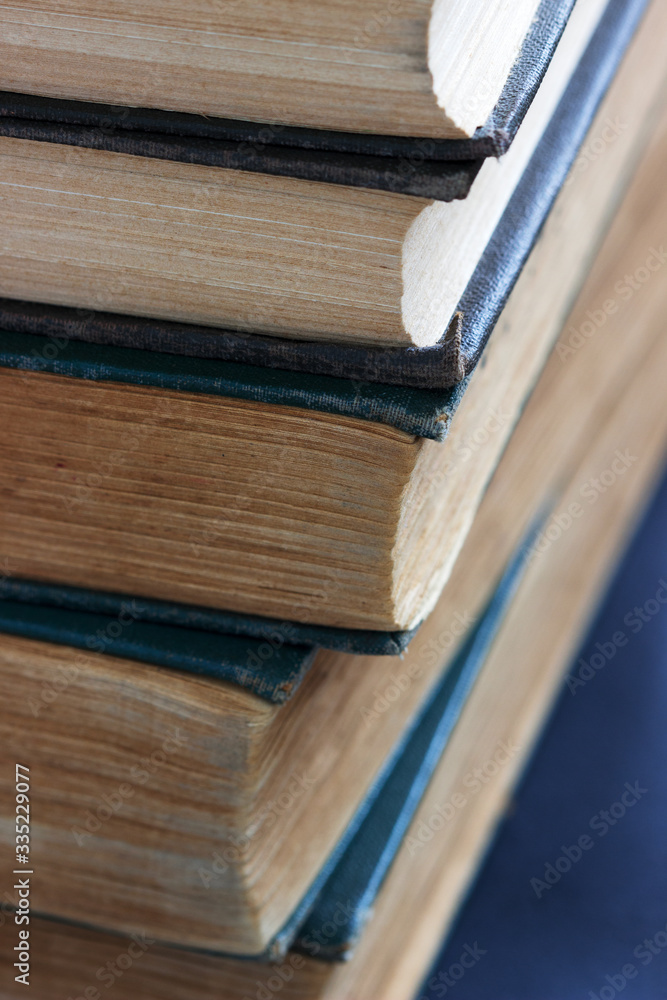 Fototapeta premium Old books with frayed covers on a dark table.