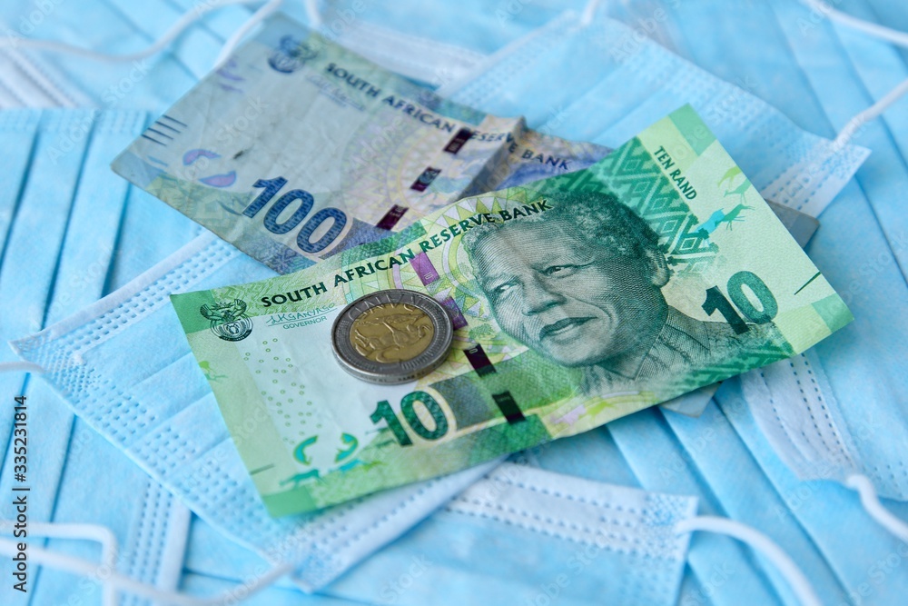 Obraz premium South African money on top of medical face masks. Cost of preventing infectious viruses such as the coronavirus (Covid-19) concept image.