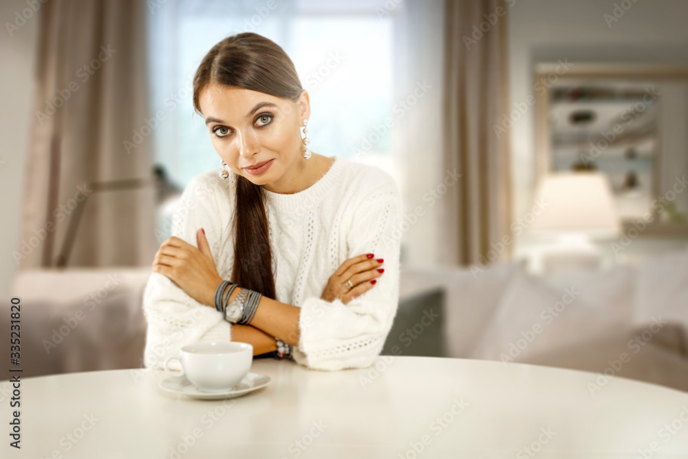 Slim young woman in home interior with blurred window and white table of free space for your decoration. Slim young woman in home interior with blurred window and white table of free space for your decoration.