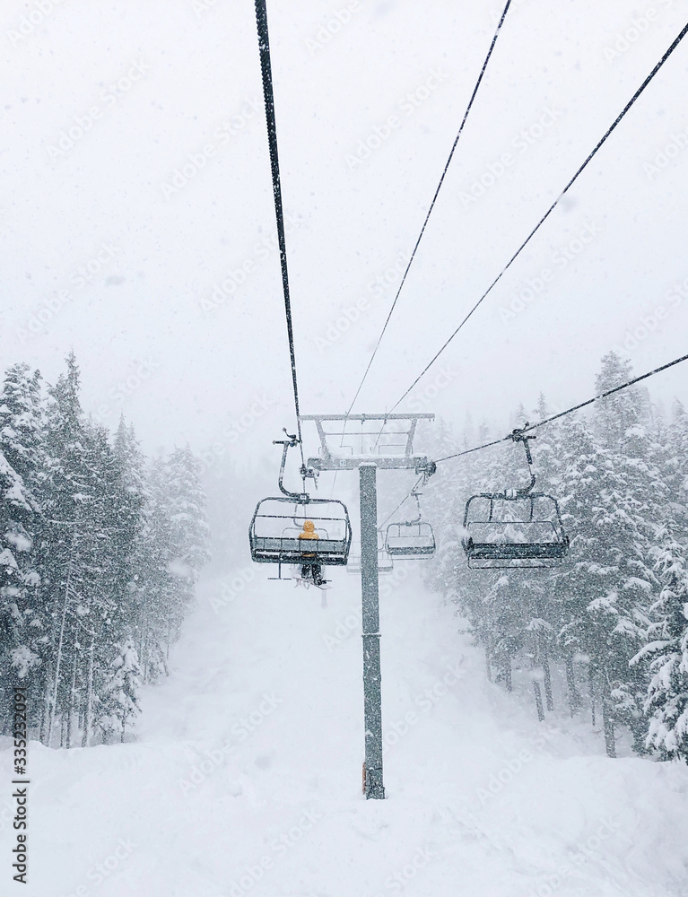 Person wearing yellow riding ski lift in the mountains Person wearing yellow riding ski lift in the mountains