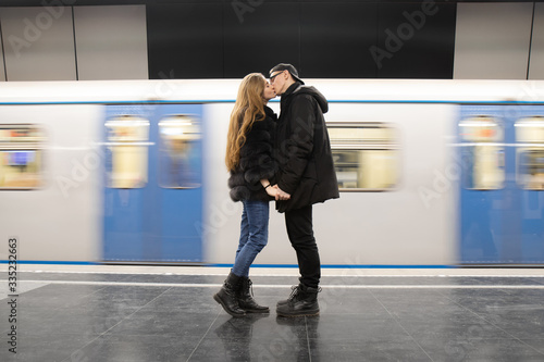 young couple kiss in the subway on the background of a moving train
