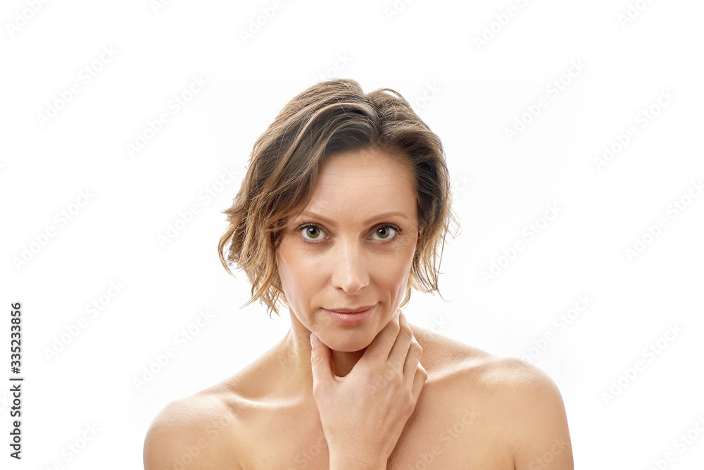 Beautiful young woman looking at the camera and touching her face. Clean skin. Naked to the shoulders posing. isolated white background. Beautiful young woman looking at the camera and touching her face. Clean skin. Naked to the shoulders posing. isolated white background.