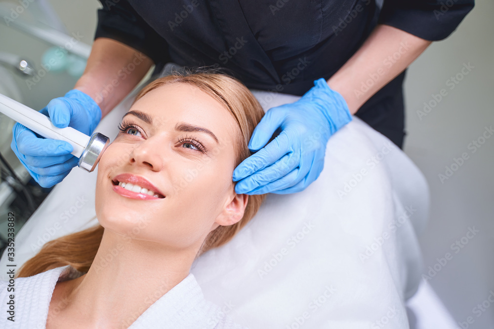 Naklejka premium Smiling jolly female at cosmetologist stock photo