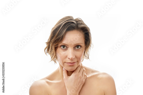 Beautiful young woman looking at the camera and touching her face. Clean skin. Naked to the shoulders posing. isolated white background.