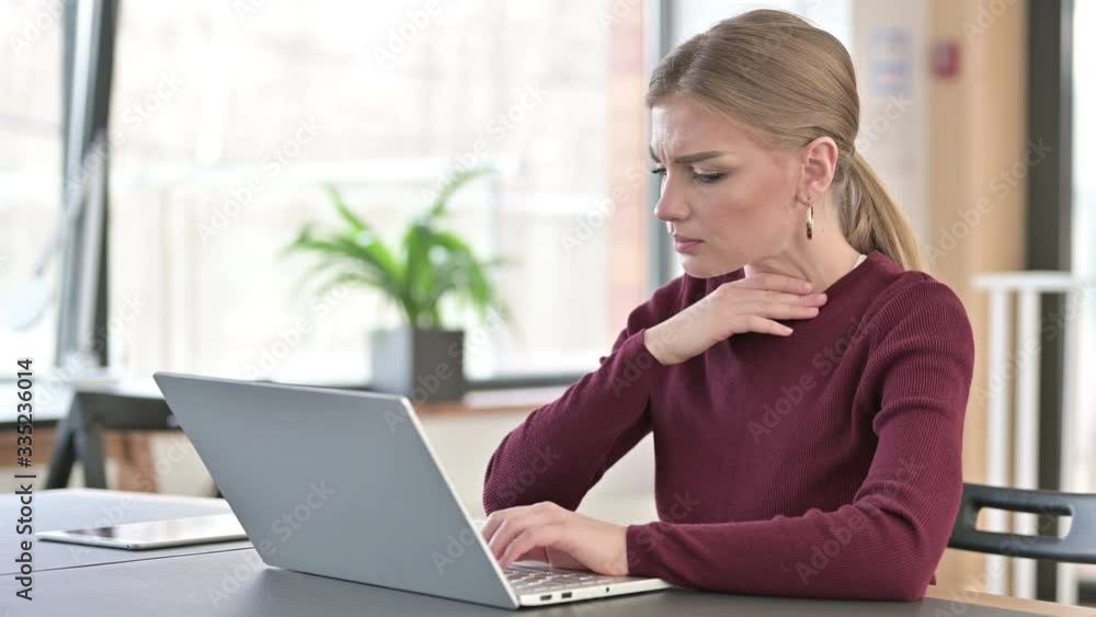 Young Woman using Laptop Coughing in Office Young Woman using Laptop Coughing in Office