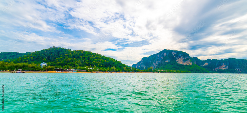 View from boat going to famous Railay beach, Krabi Thailand. Coastline of Andaman sea, famous tourist and backpacker target. Tropical paradise, exotic vacation. Cloudy weather in summer day