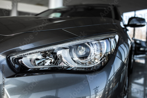 Modern luxury car close-up. Concept of expensive, sports auto. Headlight lamp of new cars,copy space. A modern and elegant car illuminated.