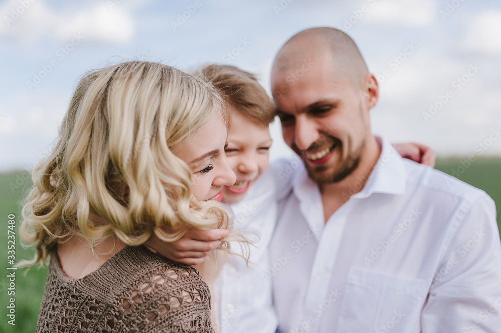 Family on a walk in a field with green grass and blue sky, early spring, good weather, happy family, white clothes Family on a walk in a field with green grass and blue sky, early spring, good weather, happy family, white clothes