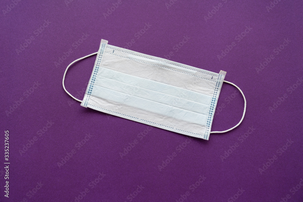 a disposable medical mask on a purple background. a disposable medical mask on a purple background.