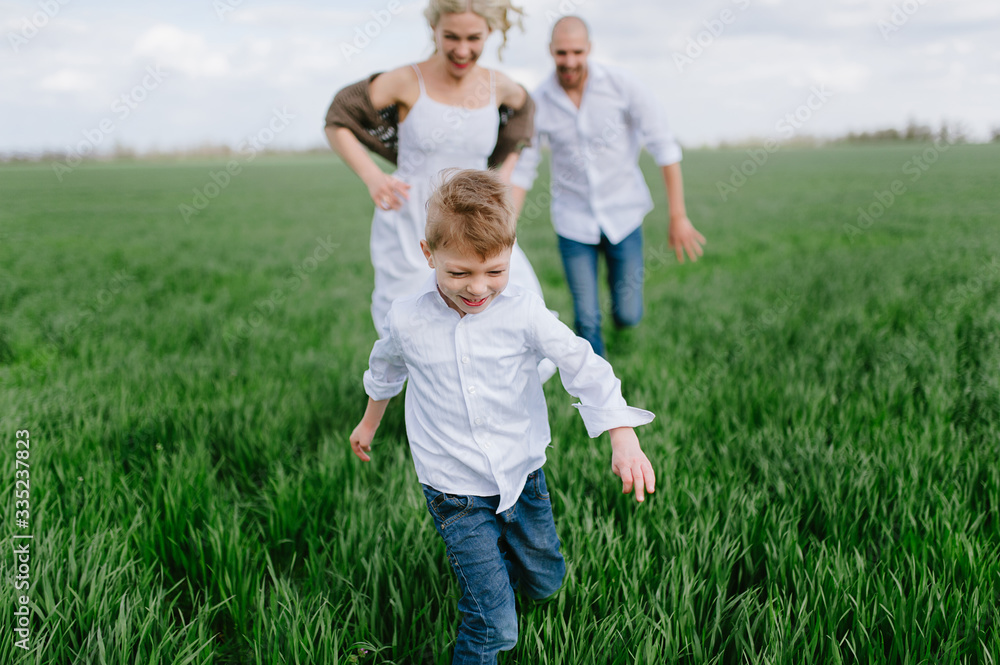 Family on a walk in a field with green grass and blue sky, early spring, good weather, happy family, white clothes Family on a walk in a field with green grass and blue sky, early spring, good weather, happy family, white clothes