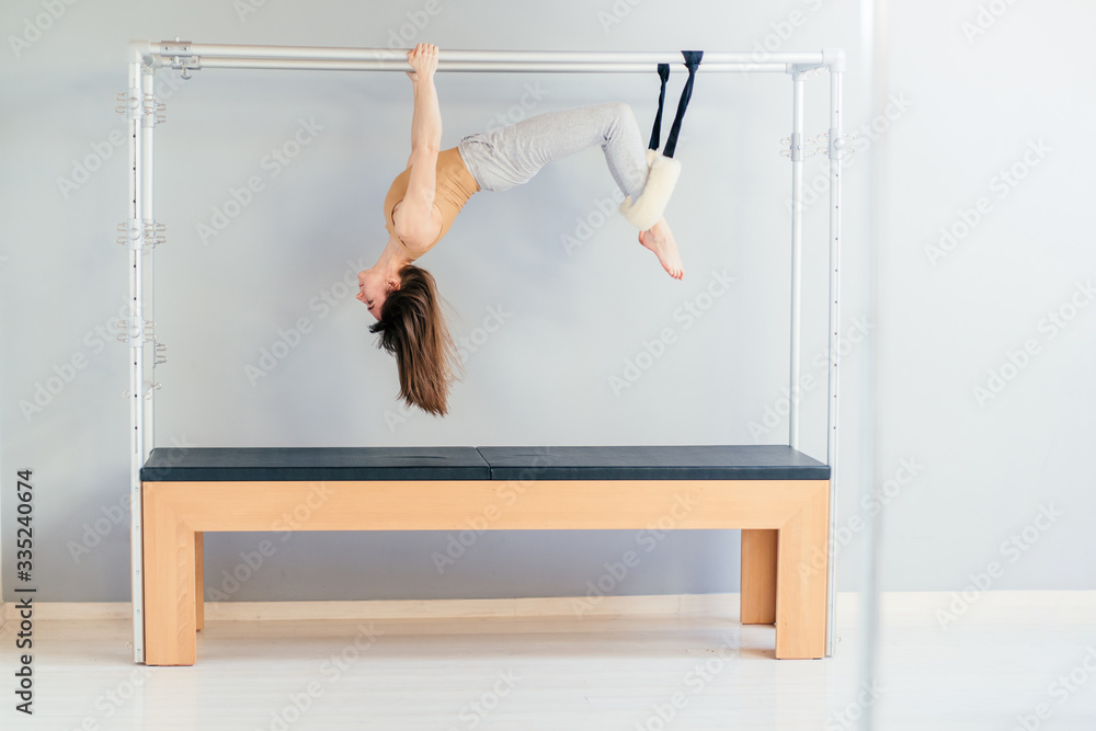 Pretty Pilates Instructor Hanging Upside Down from Trapeze Table