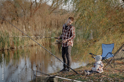 Family by the river. Guy in a red shirt. Father with in a fishing.