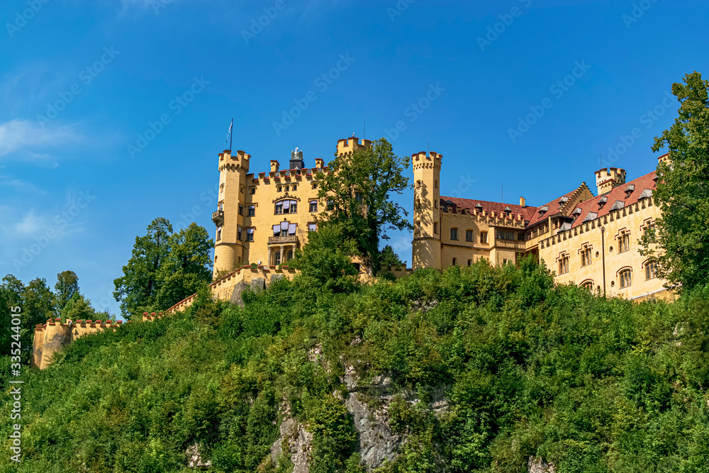 Panoramic view of the main facade of Hohenschwangau Castle in yellow. Photograph taken in Schwangau, Bavaria, Germany.