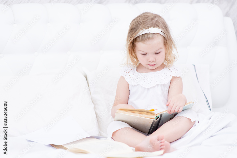 Little girl reading a book in her room in the bedroom. Home education concept. Little girl reading a book in her room in the bedroom. Home education concept.