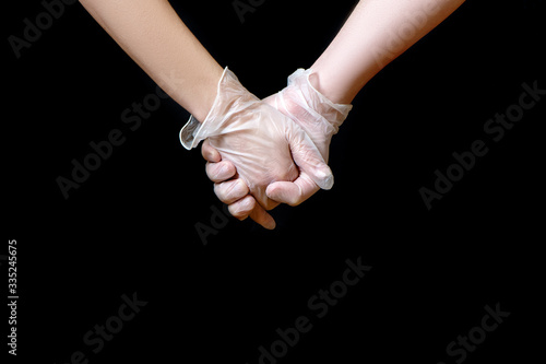 Couple holding hands in white protective gloves.