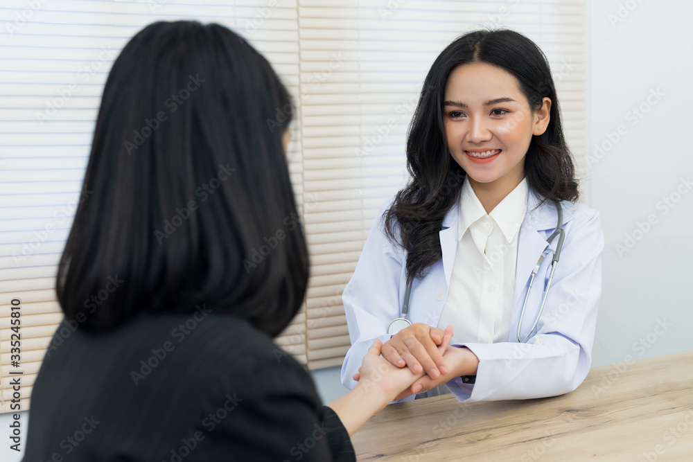 Young Asian female doctor holds adult female patient’s hand to examine and diagnose her sickness and symptom. Medicine and health care concept. Doctor and patient. Young Asian female doctor holds adult female patient’s hand to examine and diagnose her sickness and symptom. Medicine and health care concept. Doctor and patient.